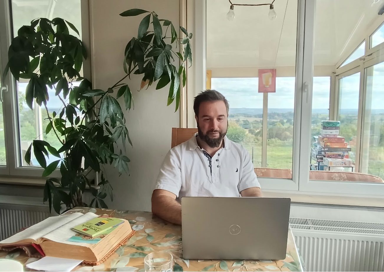 Damien au travail sur son ordinateur, face au bocage normand